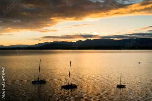 sunset over the Leman lake (Geneva lake) with sailboats and the Alps in the background