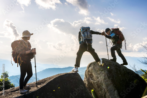 group of mountaineers people helping hands hiking to top of rock mountains