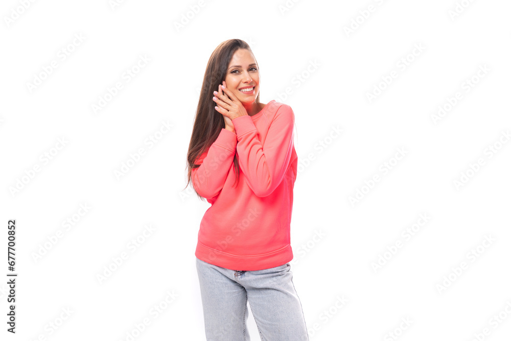 young caucasian model woman with light makeup and dark straight hair dressed in a pink sweater and jeans on a white background with copy space young caucasian model woman with light makeup and dark straight hair dressed in a pink sweater and jeans on a white background with copy space