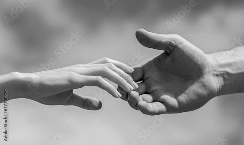 Solidarity, compassion, and charity, rescue. Lending a helping hand. Hands of man and woman reaching to each other, support. Black and white