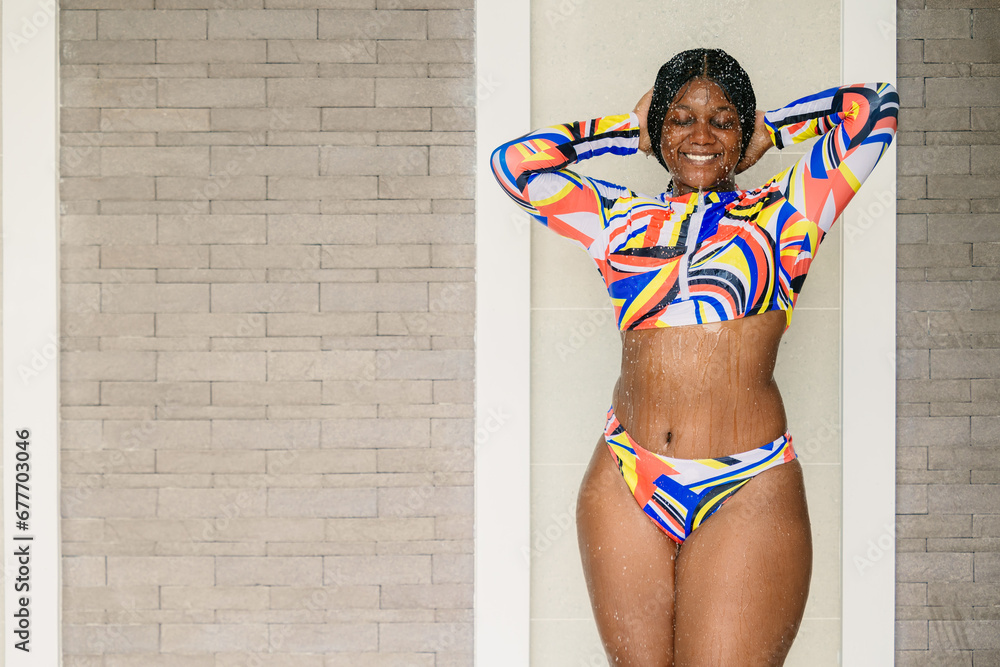 African black plus size woman enjoy refreshing splashing water at swimming pool shower happy smiling. - obrazy, fototapety, plakaty 