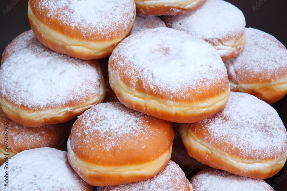 fresh bakery. fluffy fried donuts sprinkled with powdered sugar lie in a pyramid on a black table