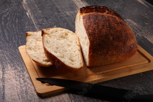fresh  bread sliced on a board/ loaf of bread with knife