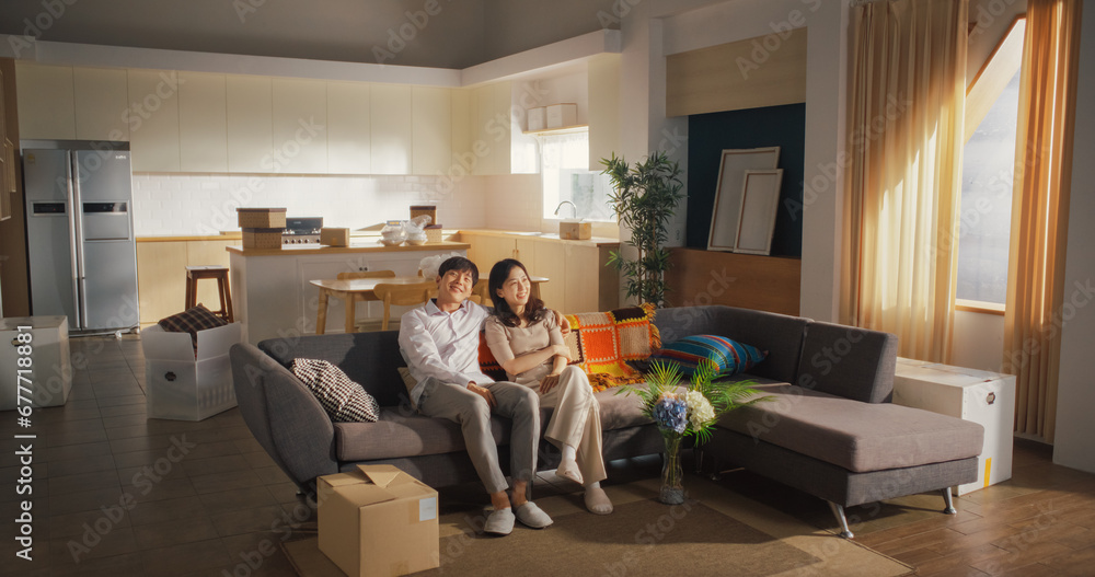 Family Moving in: Happy and Excited Young Korean Couple Sitting in Their Newly Purchased Apartment. Beautiful Family of Two Happily Embracing, Discussing How to Decorate Their New Home Family Moving in: Happy and Excited Young Korean Couple Sitting in Their Newly Purchased Apartment. Beautiful Family of Two Happily Embracing, Discussing How to Decorate Their New Home