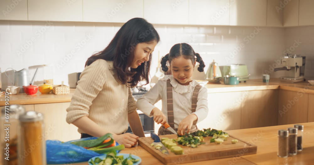 Beautiful Young Korean Mother Teaching her Cute Little Daughter How to Cook. Mother and Female Child Spending Time Together, Learning how to Use a Kitchen Knife Safely
