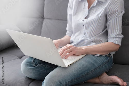 A woman is working, typing on a white laptop. Concept of online work, freelancing, training