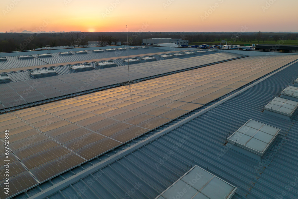 Blue photovoltaic solar panels mounted on building roof for producing clean ecological electricity at sunset. Production of renewable energy concept Blue photovoltaic solar panels mounted on building roof for producing clean ecological electricity at sunset. Production of renewable energy concept