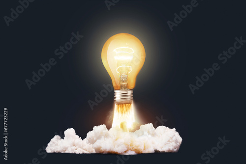Creative light bulb rocket with blast and clouds takes off on a dark background, concept. Successful launch start up, creative idea. Think differently. Creative generator. Smart and thinking photo