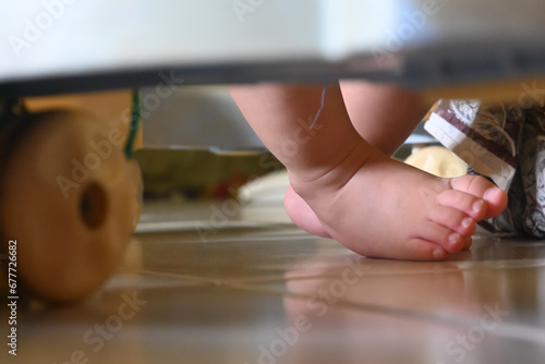 close up of a baby's feet moving on tiptoe using a baby walker that has lots of wheels. photo