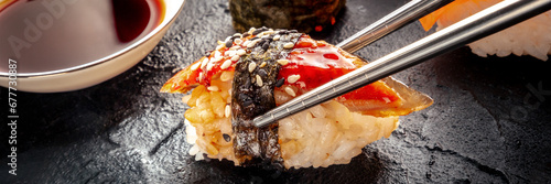 Sushi with chopsticks and soy sauce panorama. Unagi sushi, nigiri with eel, on a black background. Japanese restaurant