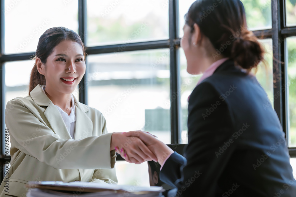 Portrait young Asian woman interviewer and interviewee shaking hands for a job interview .Business people handshake in modern office. Greeting deal concept Portrait young Asian woman interviewer and interviewee shaking hands for a job interview .Business people handshake in modern office. Greeting deal concept