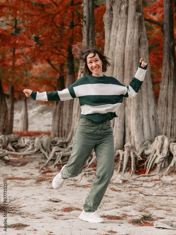 Obraz premium Lifestyle portrait of jumping woman in autumnal park. Stylish woman with emotions