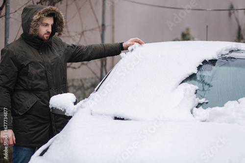 Man clean car from snow by hands after night snowfall