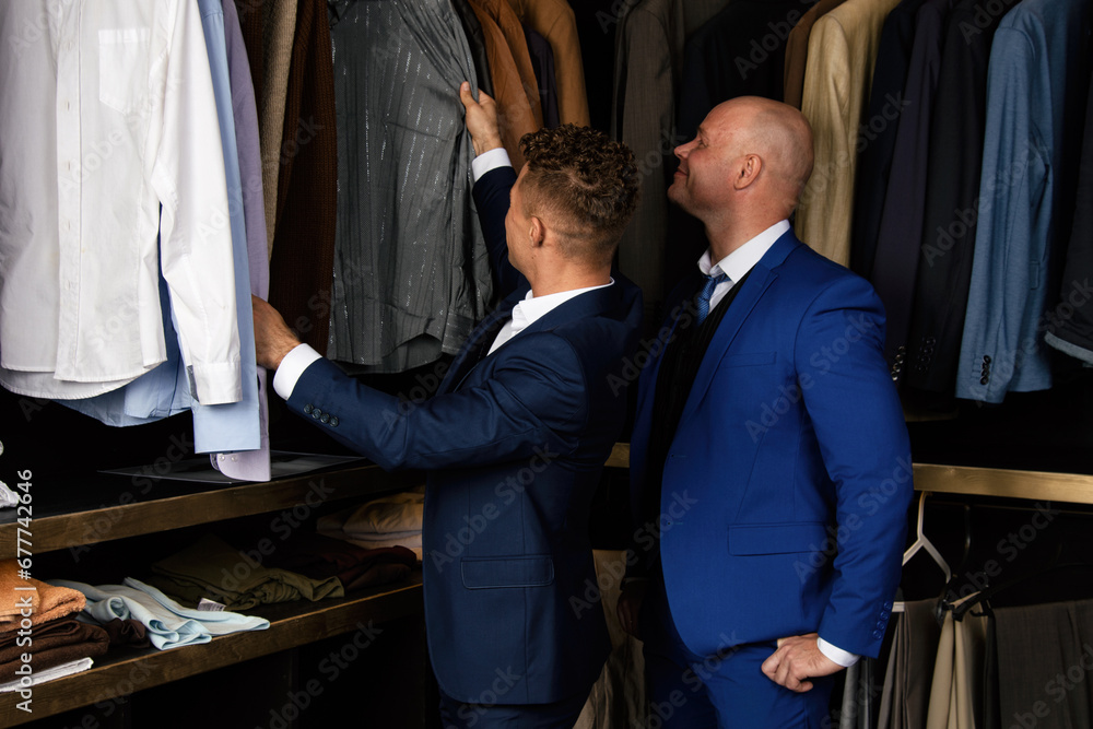 A beautiful gay couple is shopping in a store trying on clothes in the dressing room.