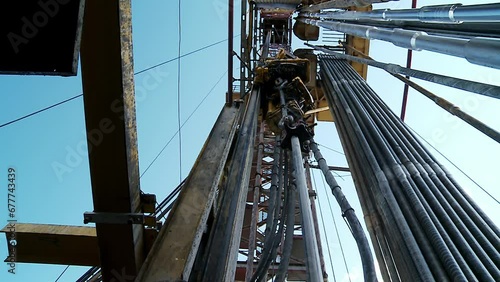 Drilling of the well.  Looking upwards inside the derrick. View of the drilling rig top with the drill pipe. 