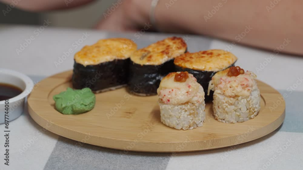 woman eating sushi, set of different rolls sushi on wooden plate, japanese cuisine close-up woman eating sushi, set of different rolls sushi on wooden plate, japanese cuisine close-up