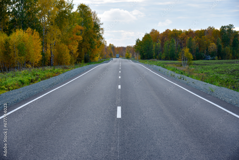 Beautiful autumn asphalt road through the forest. Highway is a road in a beautiful countryside.