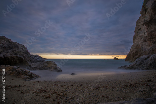 Obraz na płótnie Punta Crena, bay in Liguria, shot without swimmers on a summer evening while the sun sets behind a veil of clouds. Sunset over the sea, long exposures. Varigotti, Liguria, Italy. w salonie