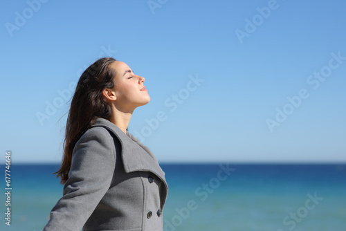 Woman in winter breathing fresh air on the beach