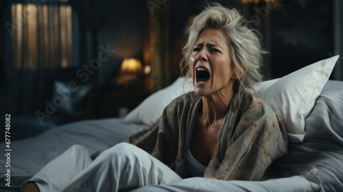 Worried mature woman yelling while lying in bed at home. Nightmare and Insomnia, horror dream and wake up emotions.