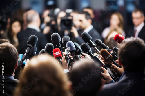 close-up captures the details of a microphone, symbolizing its central role as the hub for gathering and disseminating information among a sea of reporters