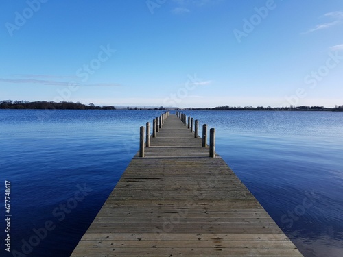 Wooden pier stretching out into the water with a blue sky in the background
