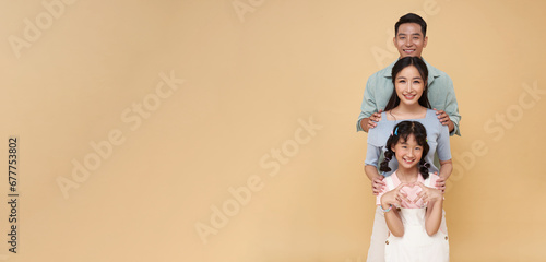 portrait happy asian family standing together isolated on nude color copy space background.
