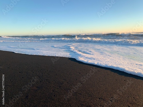 Foamy waves crashing the sandy Reynisfjara beach under scenic sunset in Iceland