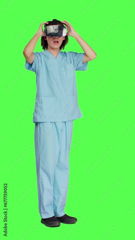 Side view of young nurse using virtual reality headset against greenscreen backdrop, working with modern interactive 3d glasses. Medical healthcare assistant working with artificial intelligence.