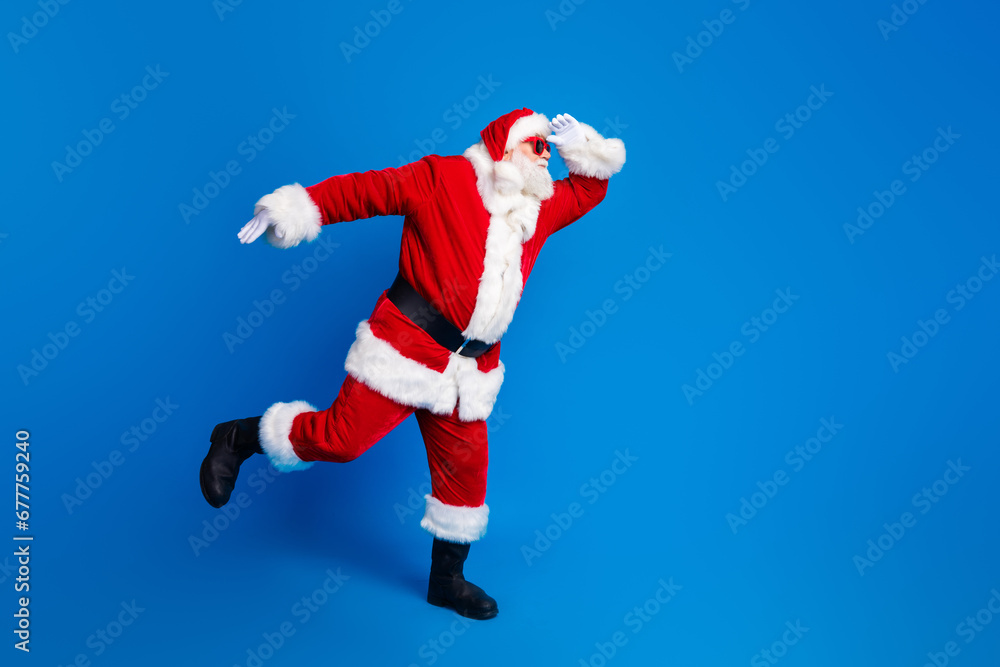 Full body photo of retired old man touch forehead look watch wear trendy santa claus costume coat isolated on blue color background Full body photo of retired old man touch forehead look watch wear trendy santa claus costume coat isolated on blue color background