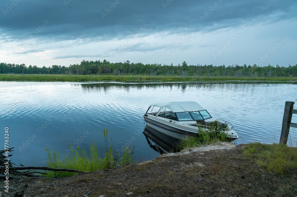 A boat sitting on the shore of a lake A boat sitting on the shore of a lake
