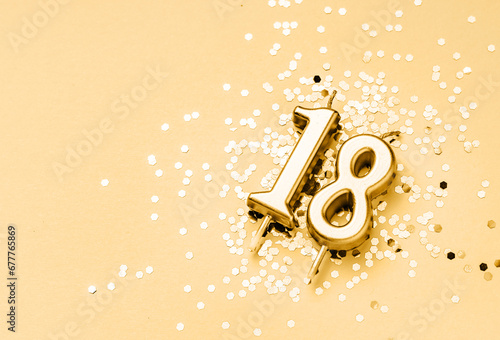 18 years birthday celebration festive background made with golden candle in the form of number Eighteen lying on sparkles. Universal holiday banner with copy space. photo