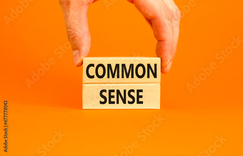 Common sense symbol. Concept words Common sense on beautiful wooden block. Beautiful orange table orange background. Businessman hand. Business, motivational common sense concept. Copy space.