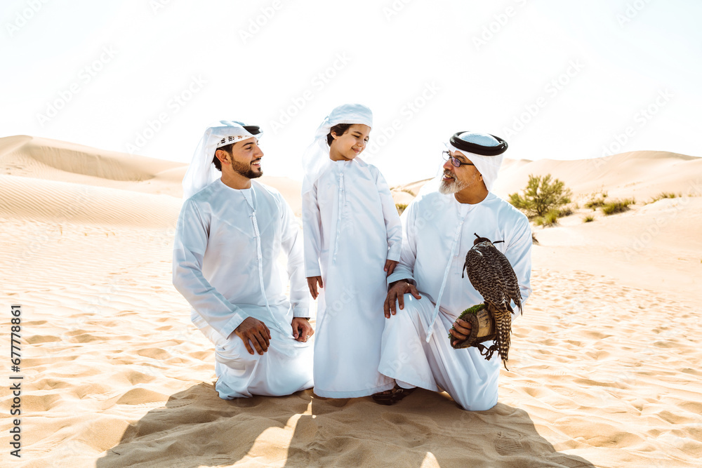 Three generation family making a safari in the desert of Dubai. Grandfather, son and grandson spending time together in the nature and training their falcon bird.