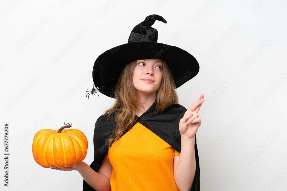 Young pretty woman costume as witch holding a pumpkin isolated on white background with fingers crossing and wishing the best Young pretty woman costume as witch holding a pumpkin isolated on white background with fingers crossing and wishing the best