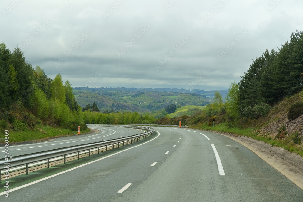 Landscape with an empty asphalt road in the forest on a cloudy spring day.