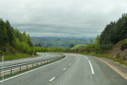 Landscape with an empty asphalt road in the forest on a cloudy spring day.