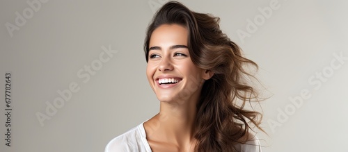 The beautiful young woman is portrayed in a modern portrait isolated against a white background with a natural and radiant smile reflecting her happy and joyful lifestyle