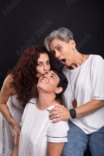 Three beautiful women, lesbians, friends happy and funny posing for the camera. Isolated on black background.