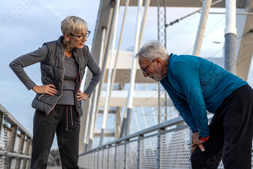 Senior adults jogging at the end of the day in sportsware on the bridge