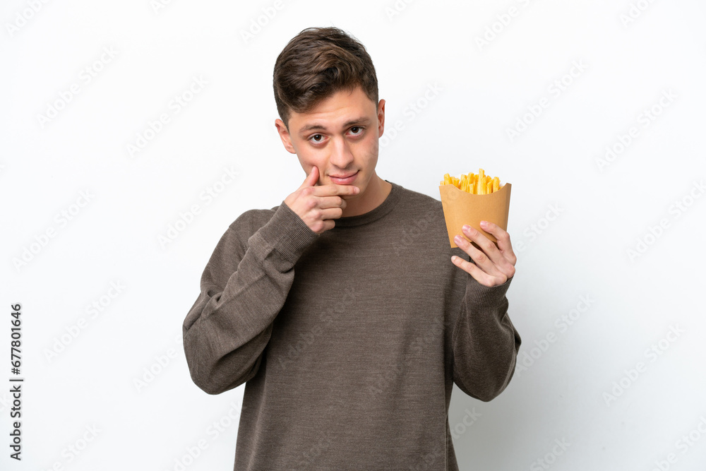 Young Brazilian man holding fried chips isolated on white background thinking Young Brazilian man holding fried chips isolated on white background thinking