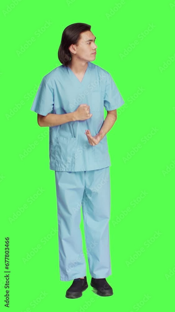 Front view over greenscreen wall, healthcare worker awaits for event, dressed in hospital protective outfit and being anxious. Man with medical expertise and natural abilities stands in studio. Front view over greenscreen wall, healthcare worker awaits for event, dressed in hospital protective outfit and being anxious. Man with medical expertise and natural abilities stands in studio.