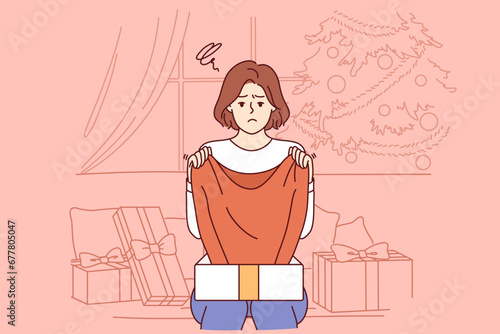 Sad woman upset by christmas gift, sitting on sofa among giftboxes near new year tree. Girl experienced stress after receiving unwanted gift or poor-quality item during christmas holidays