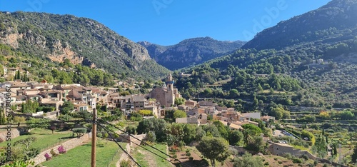 Town surrounded by mountains with dense trees on a sunny day