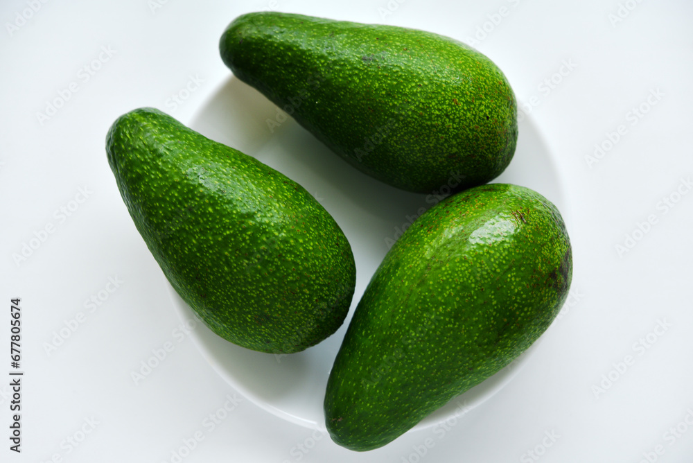 Ripe juicy avocado fruit on a white background. Vegetarian vegetables. Green fruits. Ripe juicy avocado fruit on a white background. Vegetarian vegetables. Green fruits.