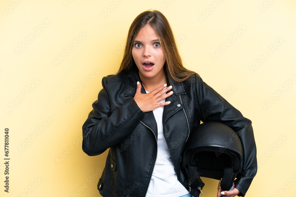 Young caucasian woman with a motorcycle helmet isolated on yellow background surprised and shocked while looking right Young caucasian woman with a motorcycle helmet isolated on yellow background surprised and shocked while looking right