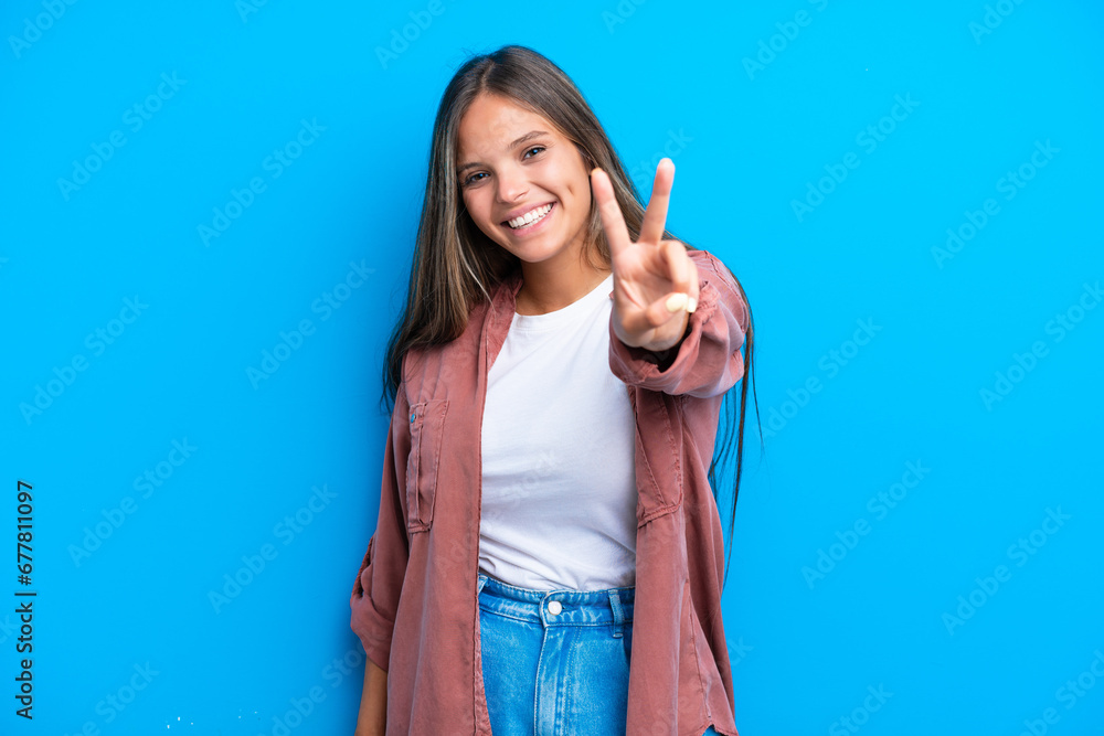 Young caucasian woman isolated on blue background smiling and showing victory sign Young caucasian woman isolated on blue background smiling and showing victory sign