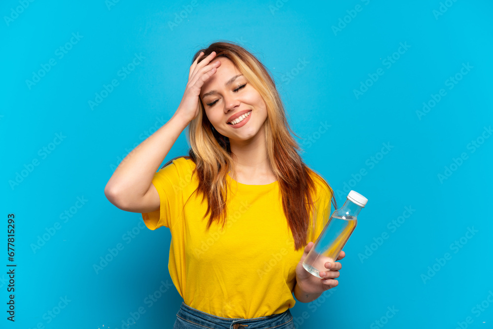 Teenager girl with a bottle of water over isolated blue background smiling a lot Teenager girl with a bottle of water over isolated blue background smiling a lot