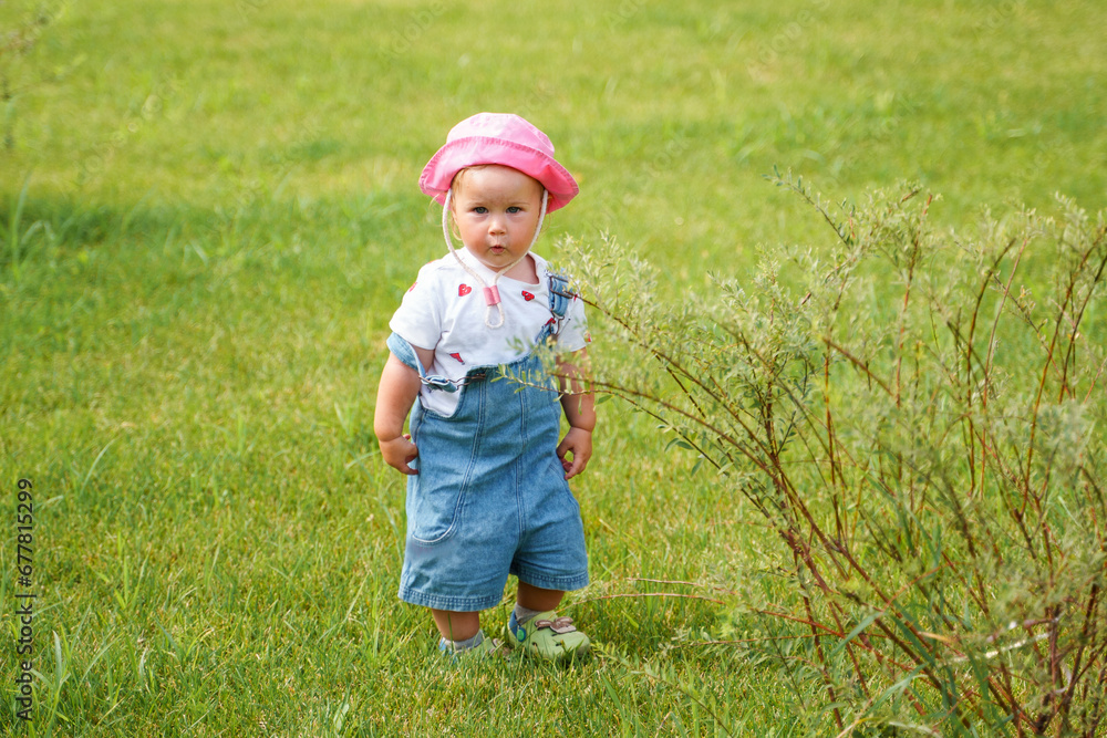 Cute baby child toddler in panama walks on a green lawn,a place for text, the concept of family and happy childhood Cute baby child toddler in panama walks on a green lawn,a place for text, the concept of family and happy childhood