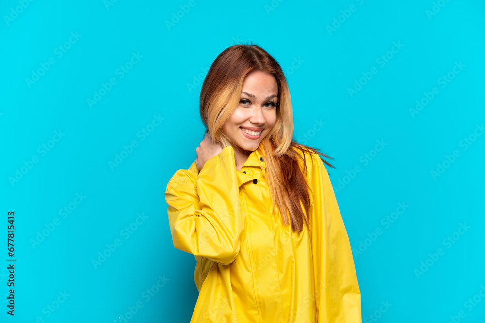 Teenager girl wearing a rainproof coat over isolated blue background laughing Teenager girl wearing a rainproof coat over isolated blue background laughing